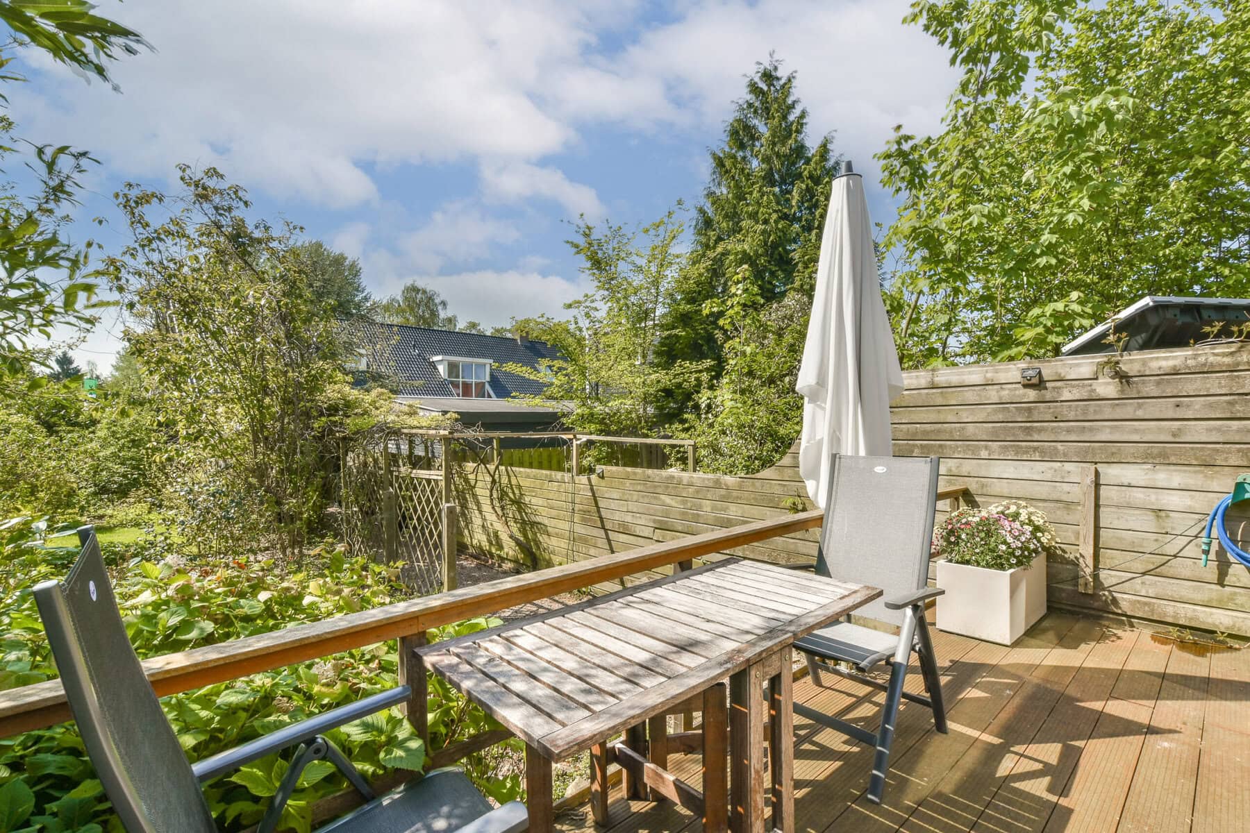 Buiten terras met tafel en stoelen in tuin, zonnige dag.