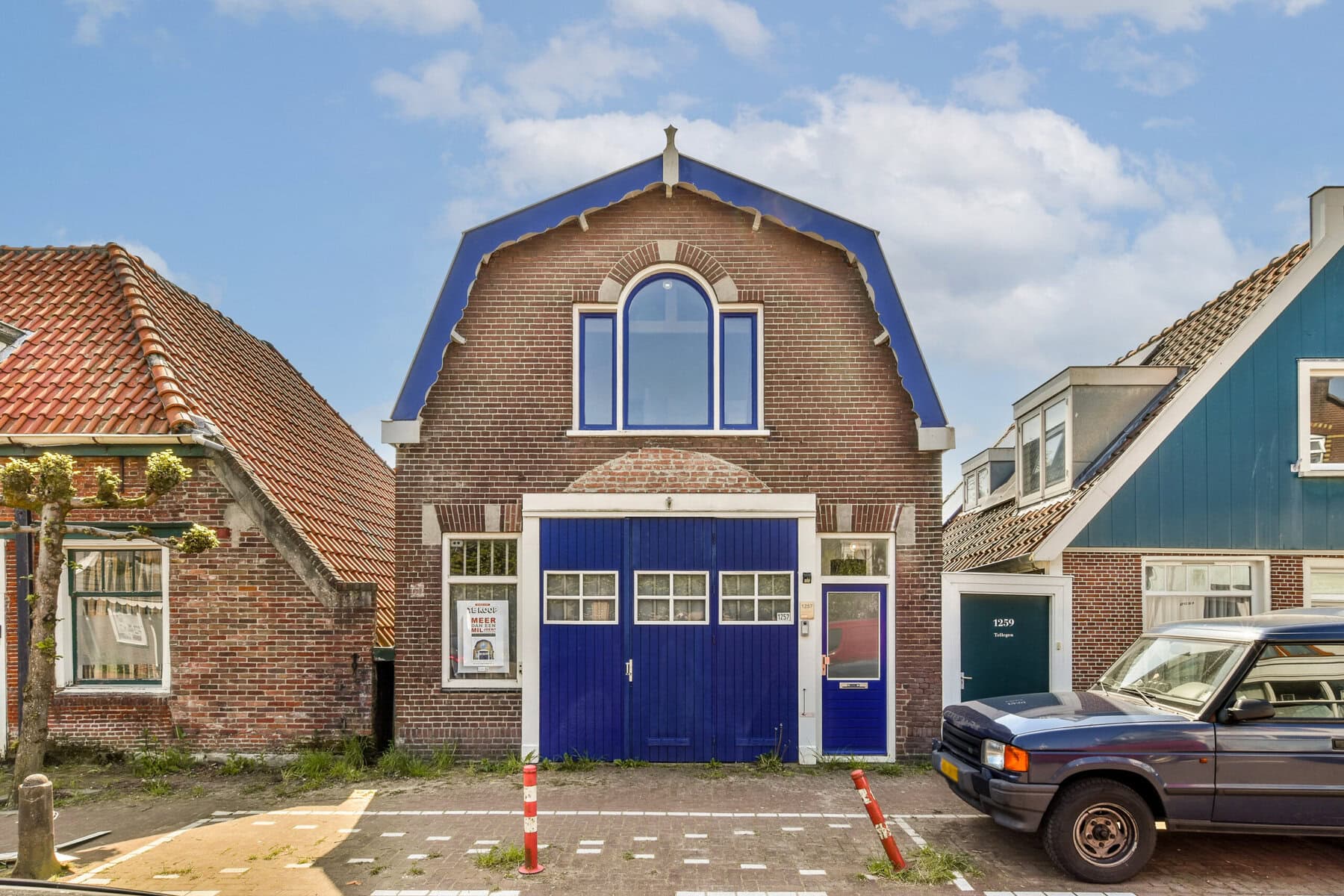 Een charmant huis met blauwe garage en grote ramen, gelegen aan de Sloterweg in Amsterdam.
