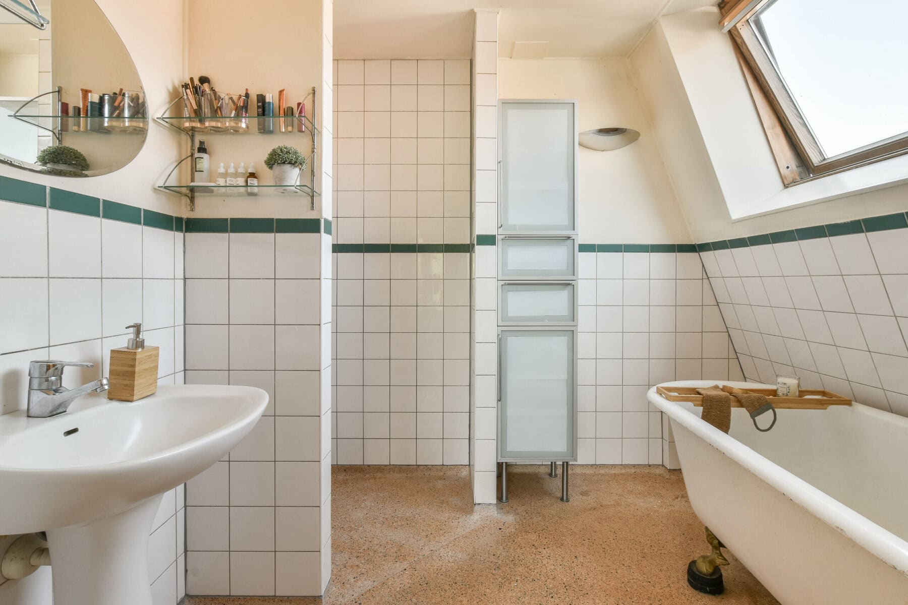 Badkamer met bad en wastafel onder schuine dakramen.
